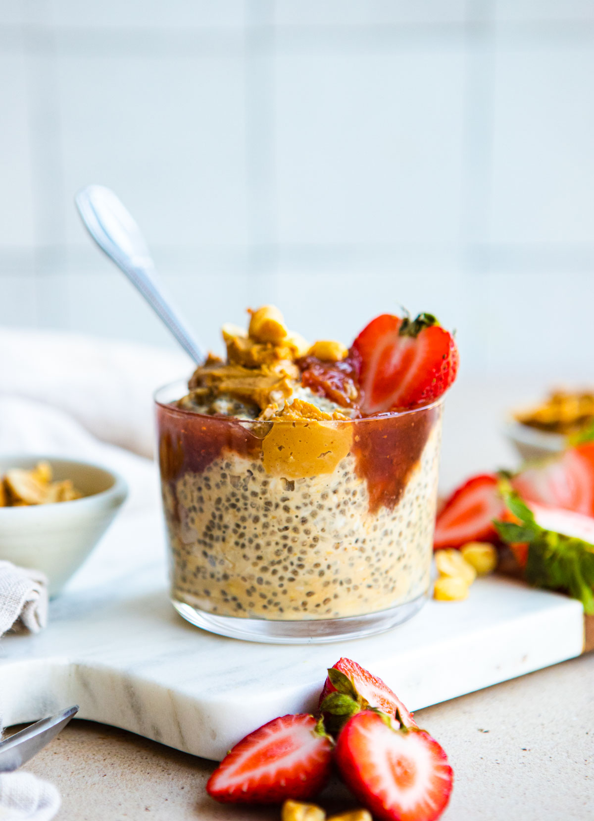 fresh strawberries topped on a glass cup filled with peanut butter and jam overnight oats 