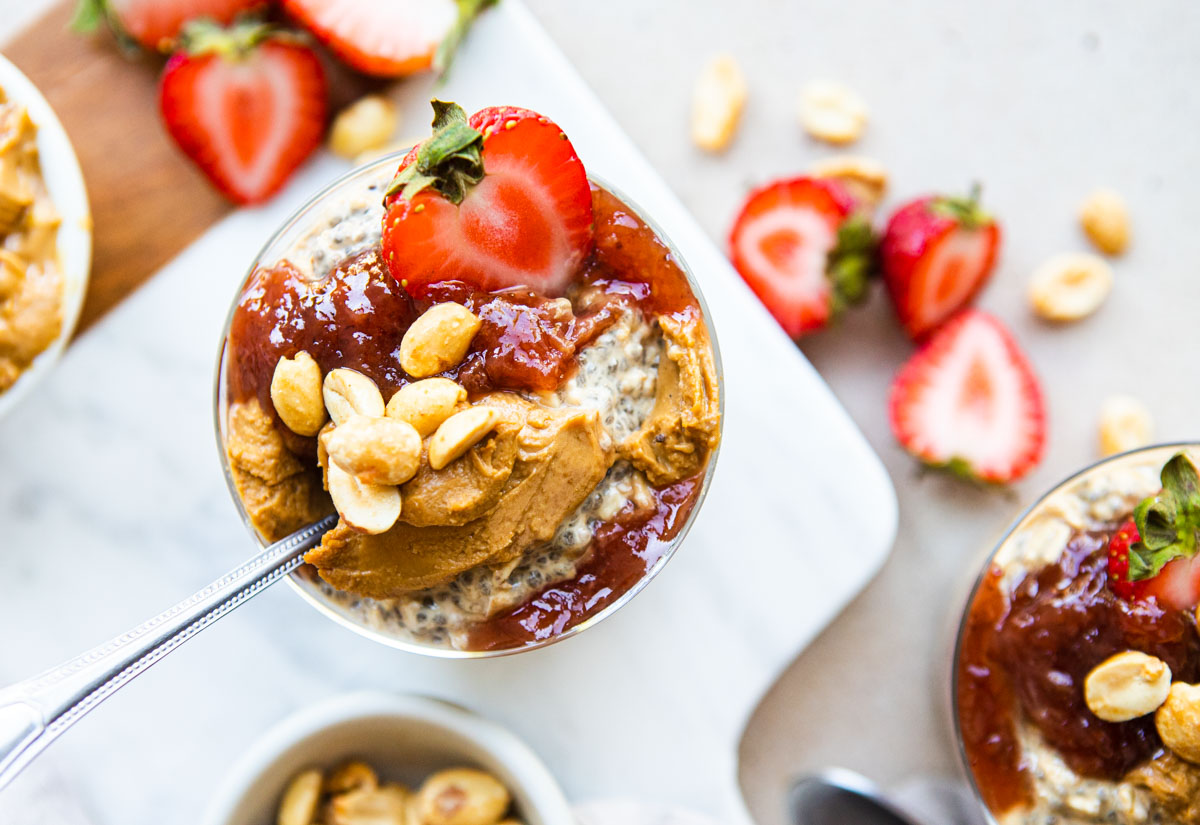 a jar of peanut butter and jelly overnight oats garnished with fresh strawberries and peanuts