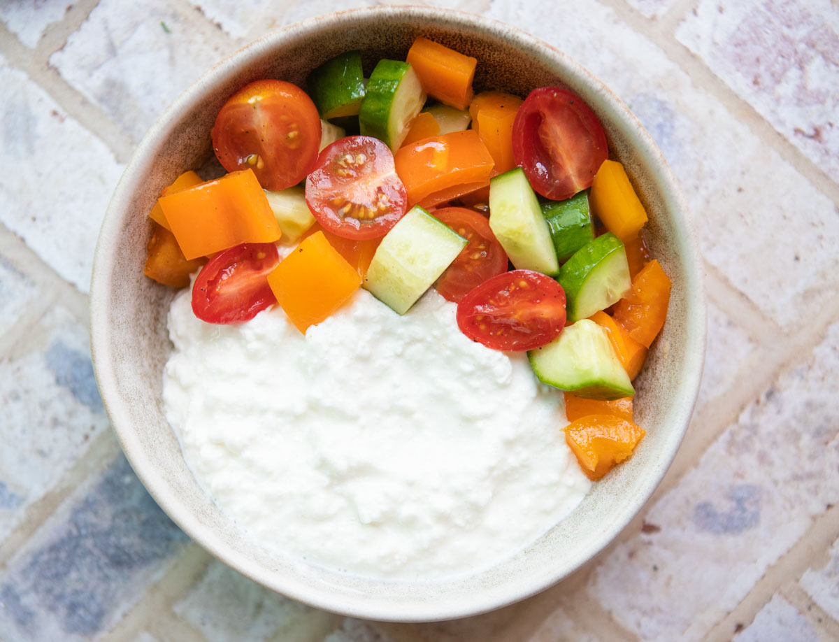 a white bowl filled with half cottage cheese and half vegetables