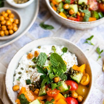 2 bowls filled with cottage cheese and veggies and garnished with mint and parsley