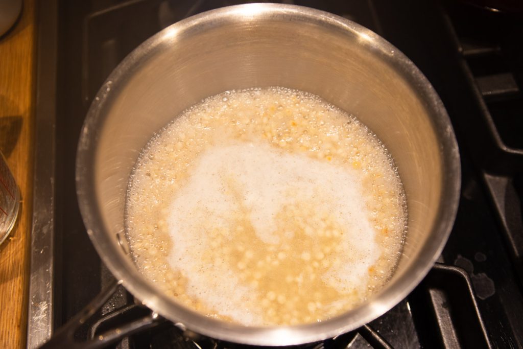 pearl couscous simmering in water on the stove