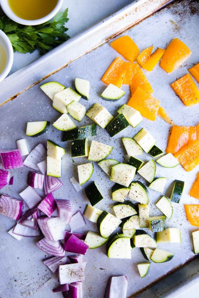 red onion, zucchini and bell pepper on a baking sheet ready to roast