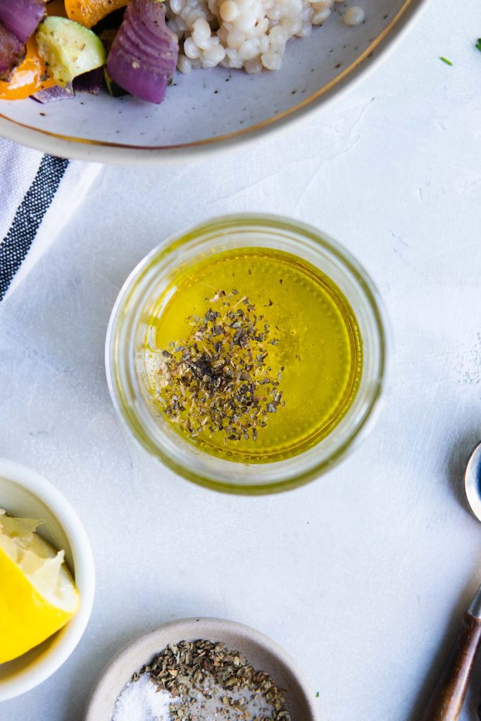 mediterranean vinaigrette ingredients added to a mason jar