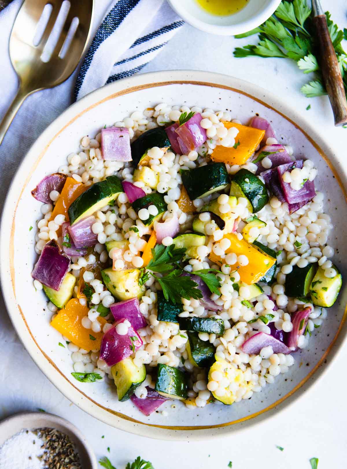 a beige bowl filled with Israeli couscous and roasted vegetables