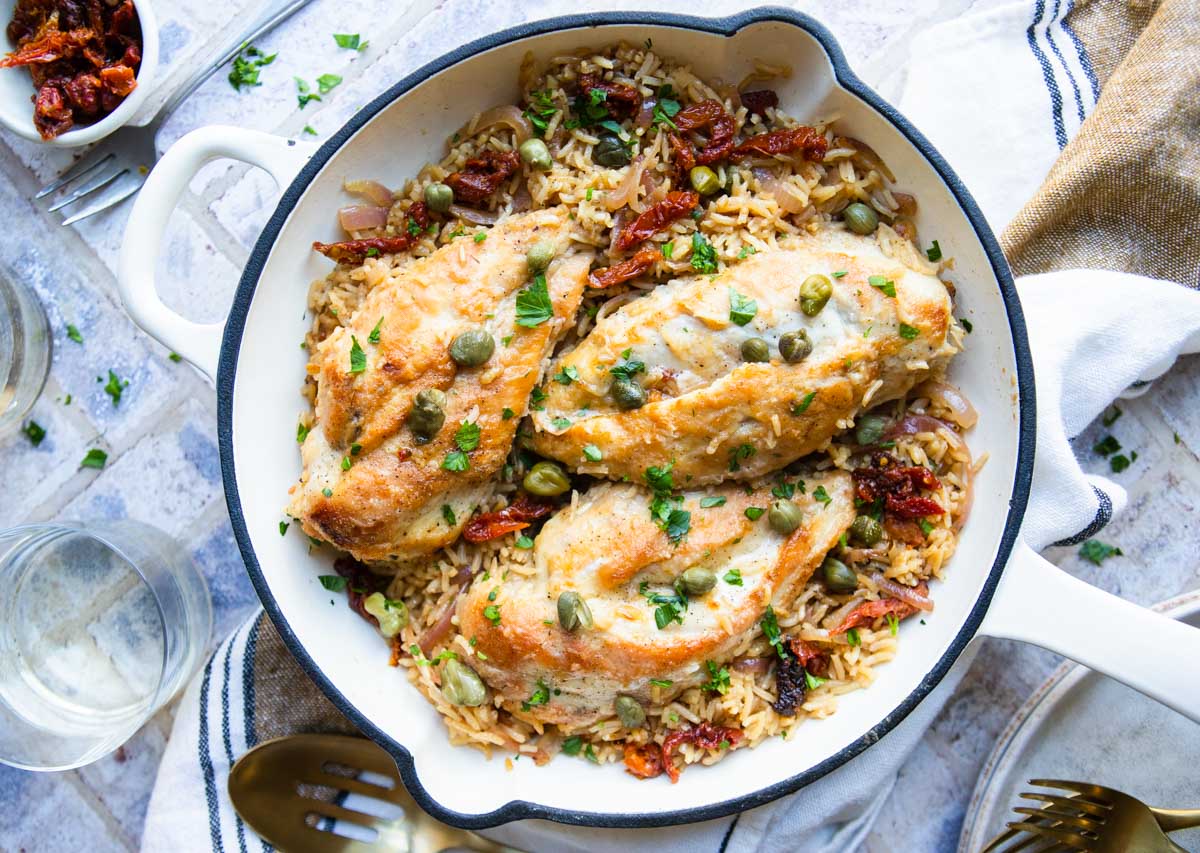 white enameled cast iron skillet with a Mediterranean rice and chicken dish