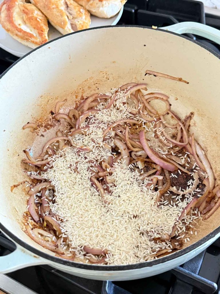 jasmine rice added to a pan with onions and garlic