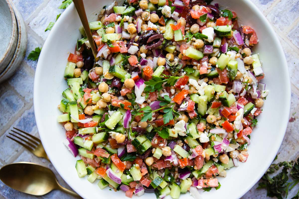 white bowl filled with a mediterranean chopped salad and garnished with parsley