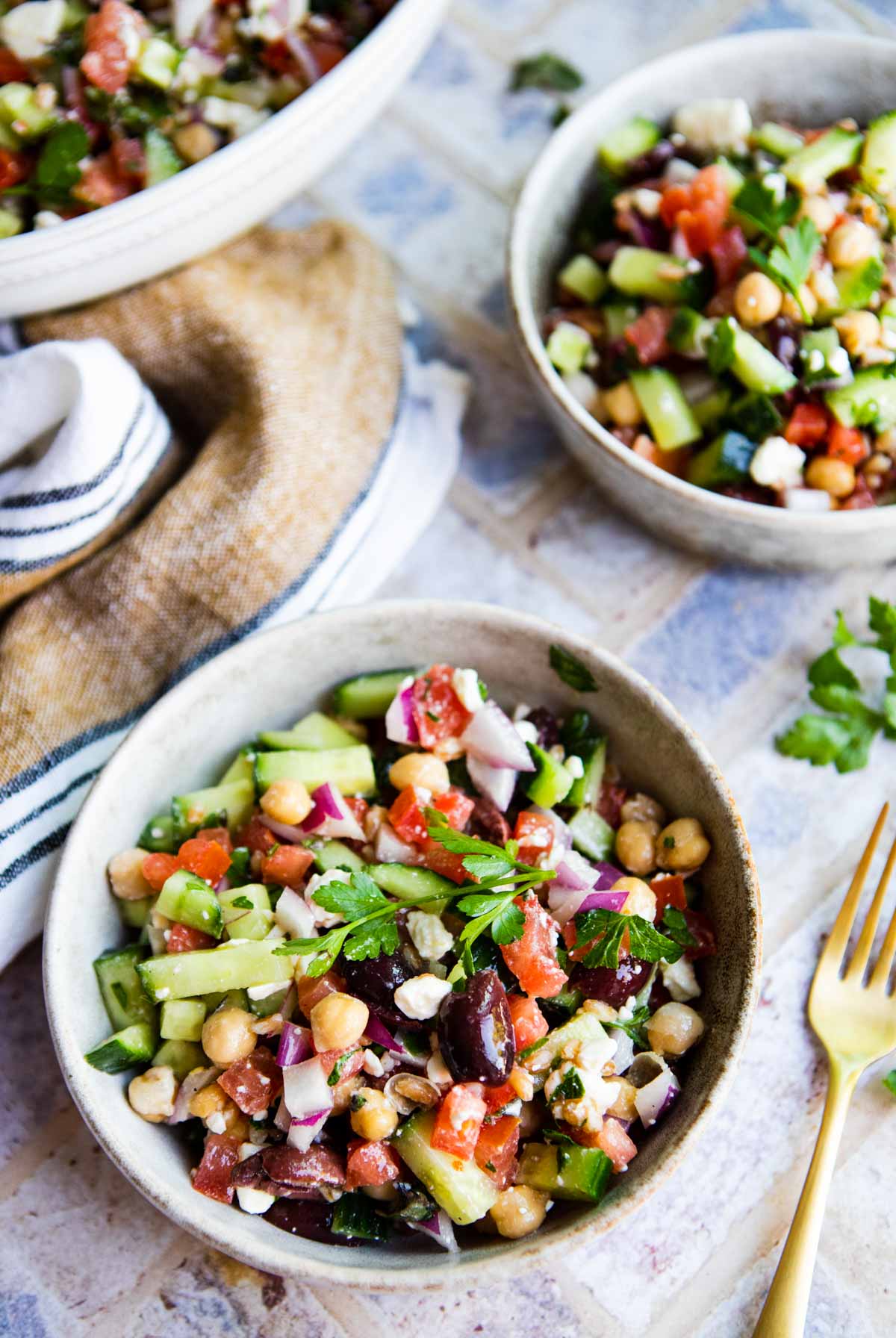 2 bowls filled with Mediterranean chopped salad set next to gold cutlery