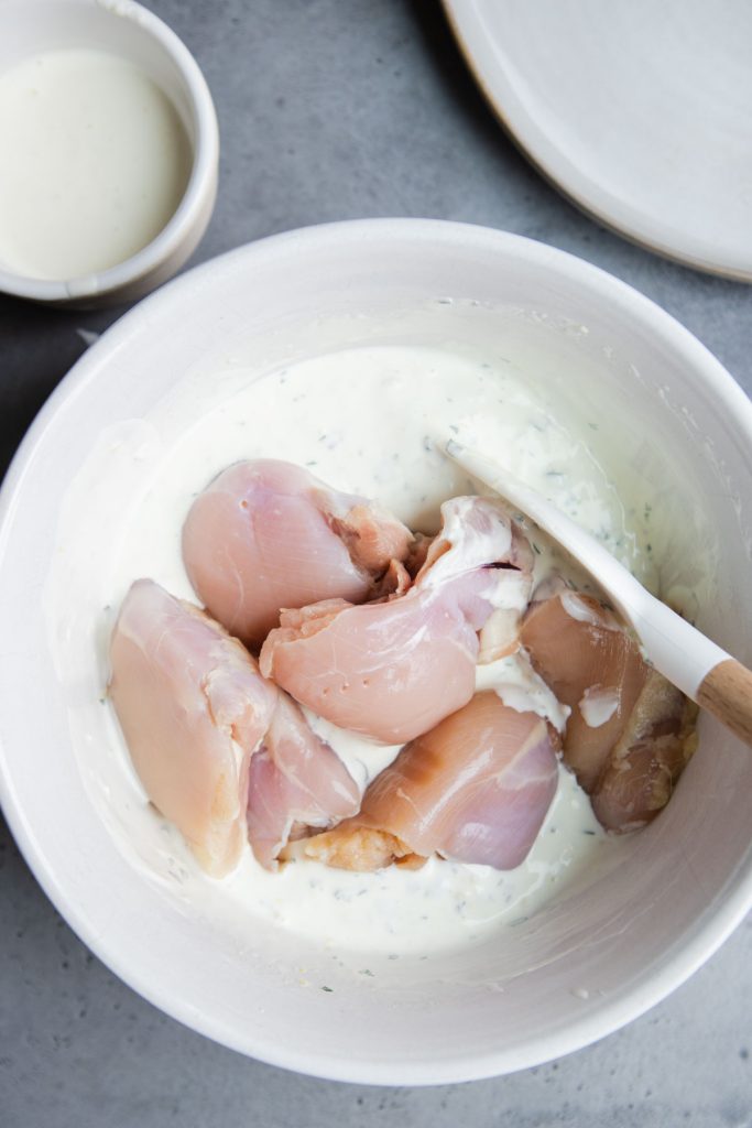 raw chicken thighs added to a chicken marinade using Greek yogurt