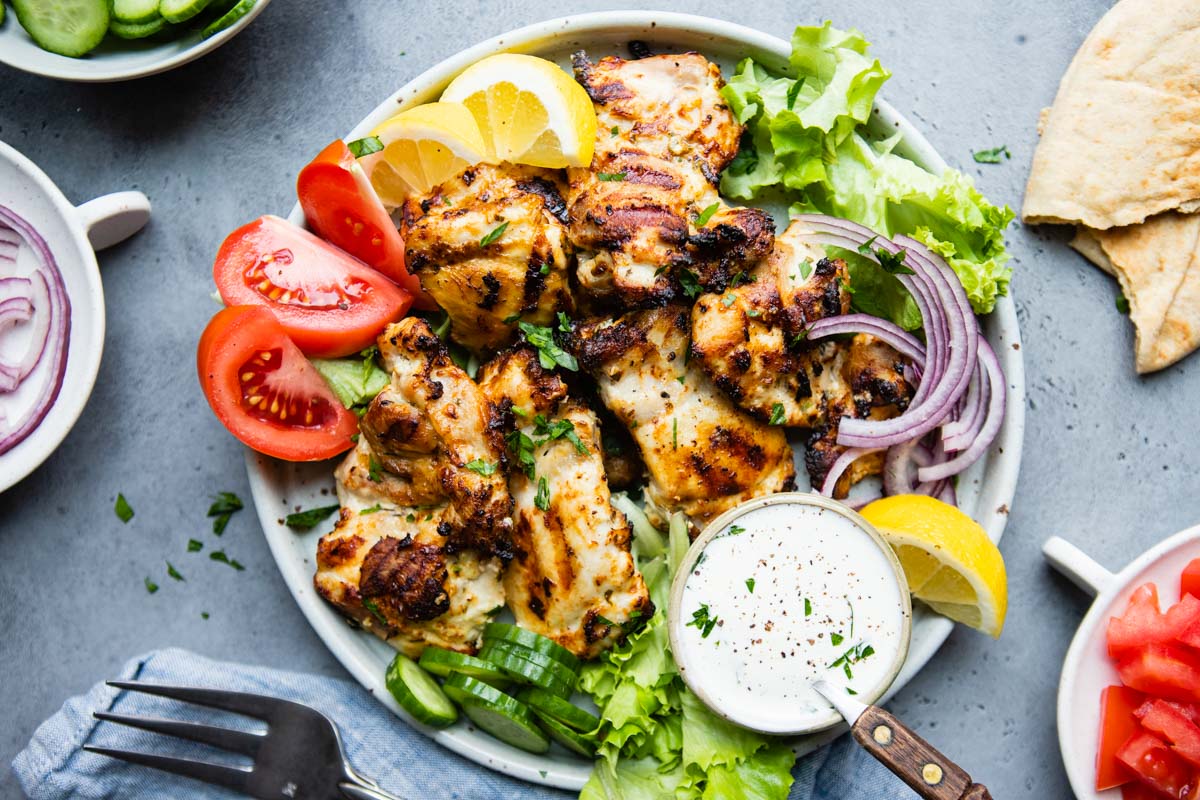 greek yogurt marinated chicken thigs grilled and plated with garnishes